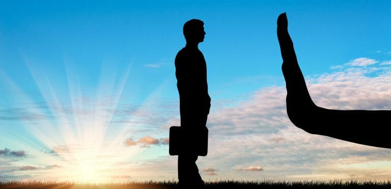 Discrimination and racism concept. Silhouettes of hands stops a man on the sunset background